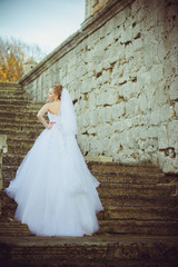 Fototapeta premium Beautiful bride walking near old castle before wedding ceremony