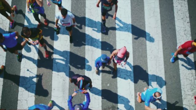 Top view of long-shadows of the runners who are walking around with their families and friends after the finish of the marathon
