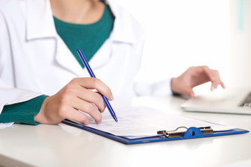 Fototapeta premium Young female student doctor writing on a white background