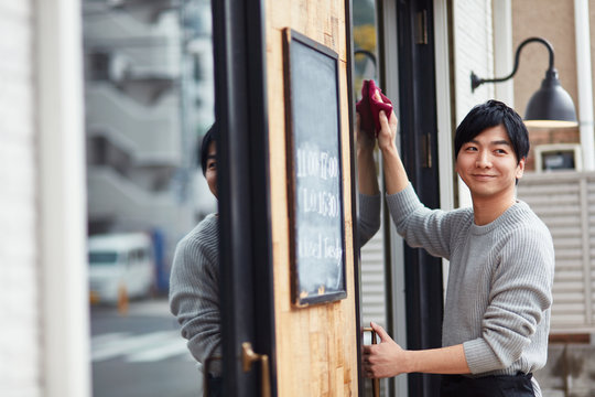 窓を拭くカフェ店員