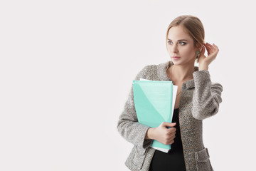 Naklejka premium young beautiful business woman in black dress, jacket holding folder of papers and smiling on gray background