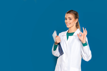 Young female student doctor with a tablet on a blue background showing signs