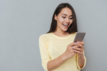 Fototapeta premium Smiling woman in sweater using smartphone