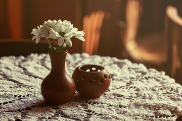 still life. A brown clay vase with chrysanthemum stands on a table with a white tablecloth in the restaurant hall