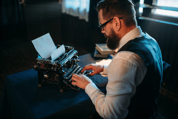 Fototapeta na wymiar Literature author in glasses typing on typewriter