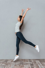 Vertical image of young woman jumping in studio
