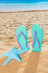 Fototapeta na wymiar Summer beach fun - summer sandals with starfish in beach sand