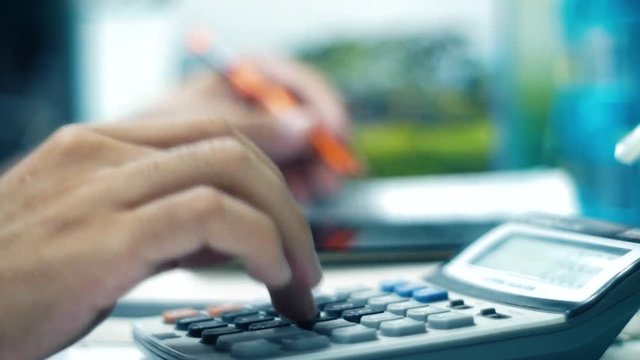 Men's hands typing on calculator