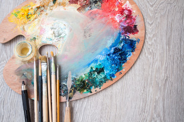 Materials for creativity, palette and brush for painting on a wooden background. The concept of fine art.