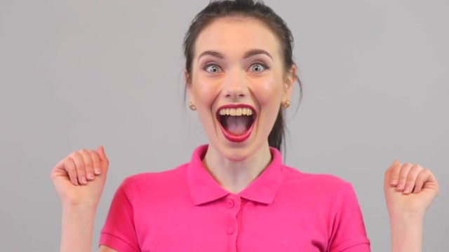 Attractive young woman ecstatic face expressions. Winning young caucasian female model in pink polo. Surprised excited happy woman closeup portrait.