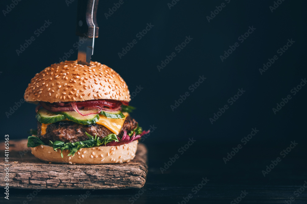 Wall mural mouth-watering, delicious homemade burger used to chop beef. on the wooden table. The burgers are inserted knives.