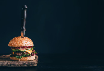 mouth-watering, delicious homemade burger used to chop beef. on the wooden table. The burgers are inserted knives. - obrazy, fototapety, plakaty