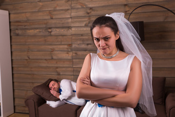 Unhappy bride, sleeping groom on background