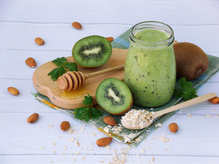 healthy green smoothies from kiwi, oatmeal, nuts and honey on light background.