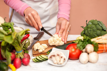 Woman cutting fresh cauliflower with a knife