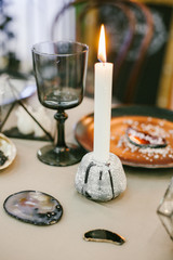 Stone candlestick with candle, glass and other elements of festive table wedding centerpieces decorations.