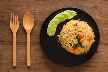 Fried rice with cucumber on black circle plate on wooden table