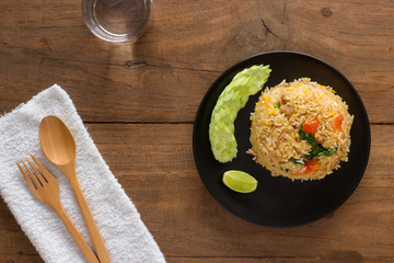 Fried rice with cucumber on black circle plate on wooden table