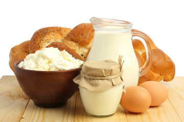 Glass jug pitcher of fresh milk with glass, eggs and cottage cheese on wood table isolated on white background carafe