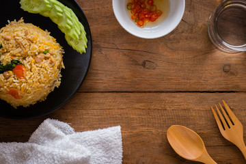 Fried rice, wooden fork and spoon with chili fish sauce on wooden table with copy space