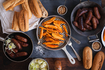 Party table with grilled sausages and sweet potatoes fries.