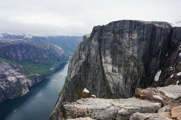 panoramic view of huge Norwegian mountain in front of fjord in cloudy day