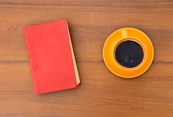 Cup of coffee and old book on wooden desk