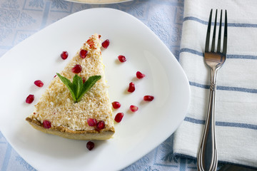 Homemade coconut cream pie in white plate with fork on light cloth napkin