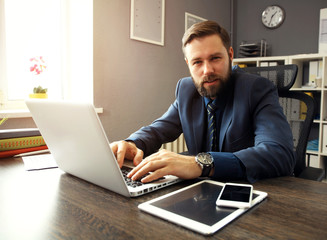 Handsome businessman working with laptop in office.