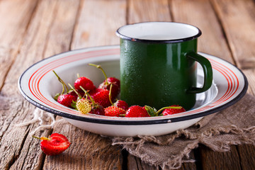 Fresh Strawberries and Blueberries  in the Iron bowl with a Cup of Milk on Vintage Wooden Background.Food or Healthy diet concept.Copy space for Text. selective focus.