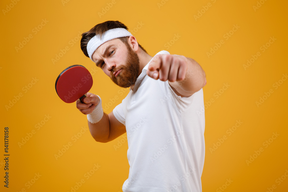 Wall mural Young sportsman holding racket for table tennis while pointing.