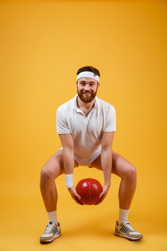 Happy young sportsman make sport exercises holding ball.