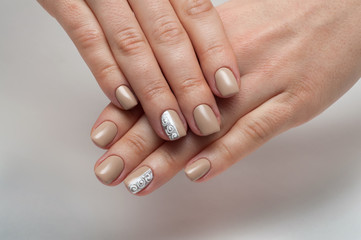 Delicate beige manicure on short square nails with silver and monograms on a white background 
