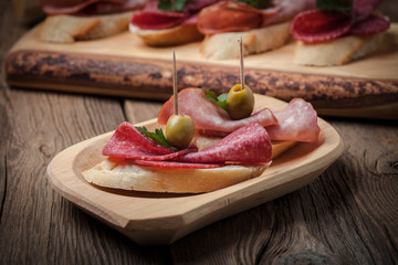 Tapas with sliced sausage, salami, olives and parsley.