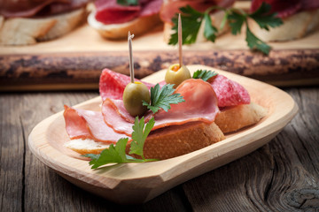 Tapas with sliced sausage, salami, olives and parsley.