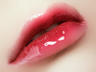 Close-up beautiful female lips with bright lipgloss makeup. Perfect clean skin, light fresh lip make-up. Beautiful spa macro shot with tender pink lip gloss. Spa and cosmetics
