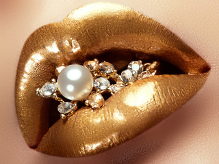 Cosmetics and make-up. Closeup of gold artistic lips. Glitter shiny lip makeup. Shoot of a...