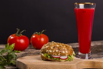 Healthy sandwich made with whole grain bread, lettuce, tomato, radish, cheese and roasted chicken slices.