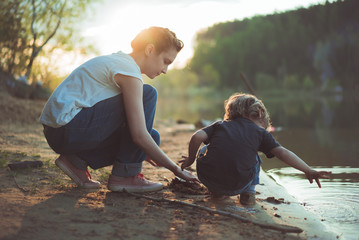 Мама и сын на берегу озера компает песок на закате