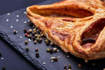 Home made, puff pastry with meat and spices on the black background. Macro.