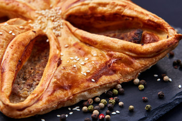 Home made, puff pastry with meat and spices on the black background. Macro.