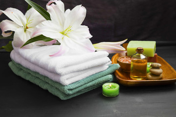 Obraz na płótnie Canvas Spa set with soft towels, candles, bath oil, soap and salt.Lily flowers and aromatherapy