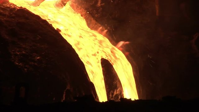 Hot metal pout out from blast furnace. Liquid metal pouring from blast furnace. Molten metal pouring from industrial furnace. Liquid steel falling from blast furnace. Liquid iron flow