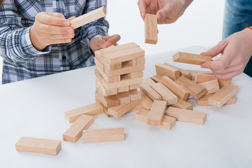 Fototapeta na wymiar Game of physical and mental skill. Keep balance. girl builds tower of wood blocks. Entertainment activity. Education, development. The girls collect a sprawling constriction of wooden Blocs 