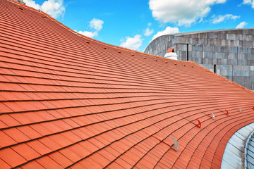 Naklejka premium Tile roof with blue sky and clouds in background