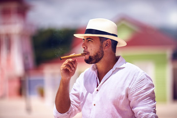 confident bearded man smoking cigar on caribbean street