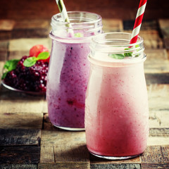 Smoothies from blackberries and strawberries in glass bottle, vintage wooden background, selective focus