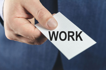 Business man in blue suit, close-up of hand showing card with text work.