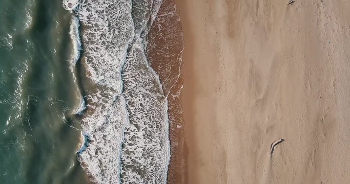 Aerial view of the beach and waves at sunset