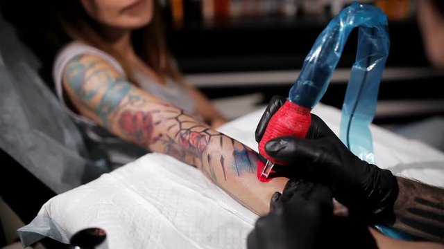 Professional tattoo artist makes the gradient tattoo on a young girl's hand. Close up